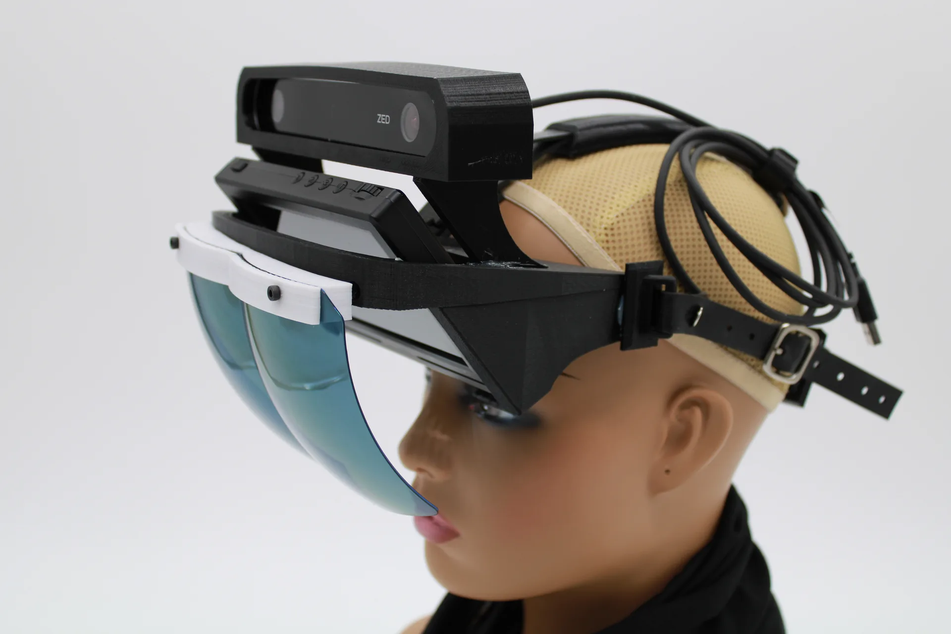 Side view of a mannequin head wearing a black HoloFlect build with a ZED stereo camera on top, a display housing beneath it and a blue visor.