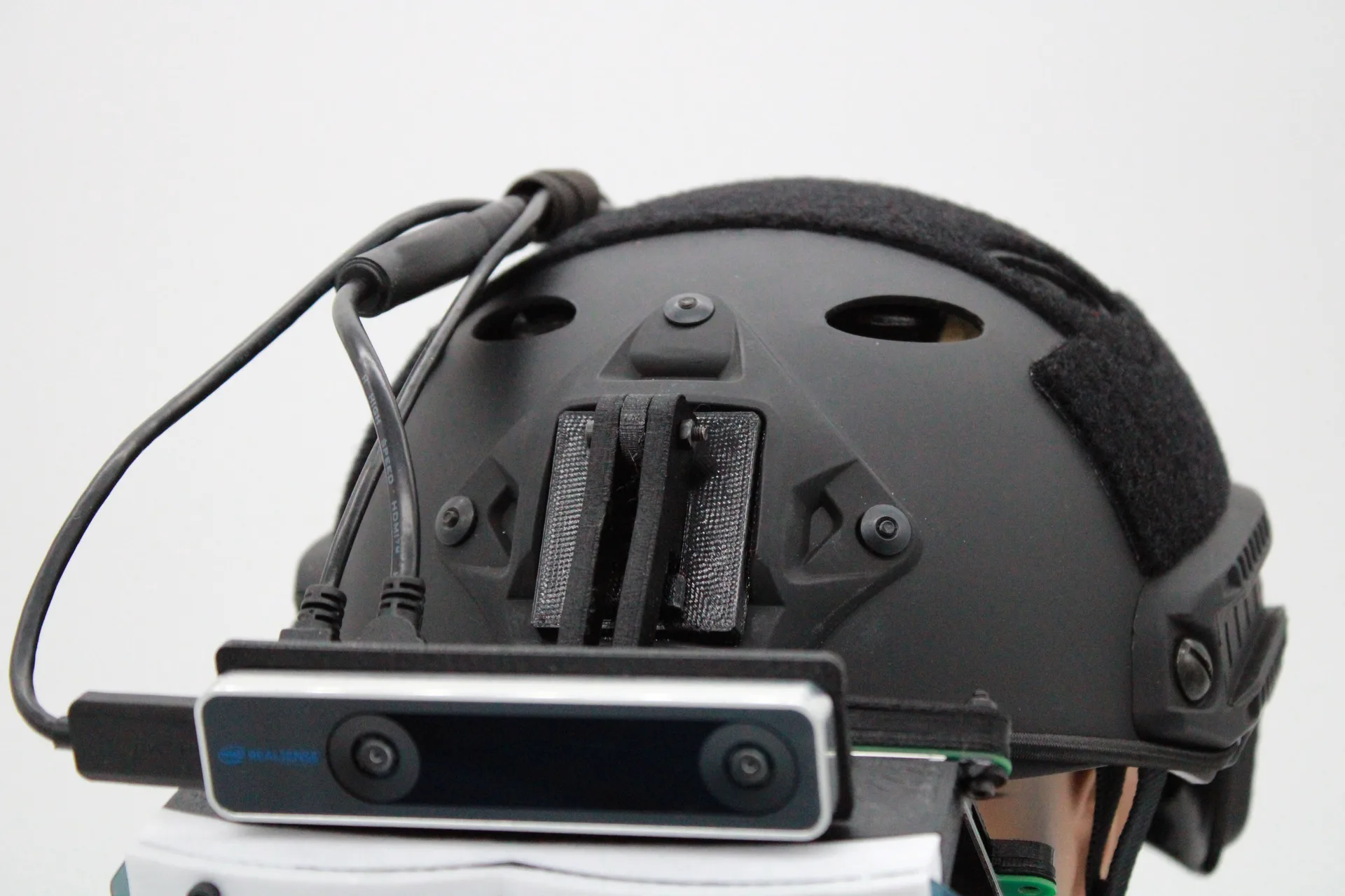 Close-up of the top of a black tactical helmet, showing a printed rail mount and a tracking camera on a bracket at its front edge.