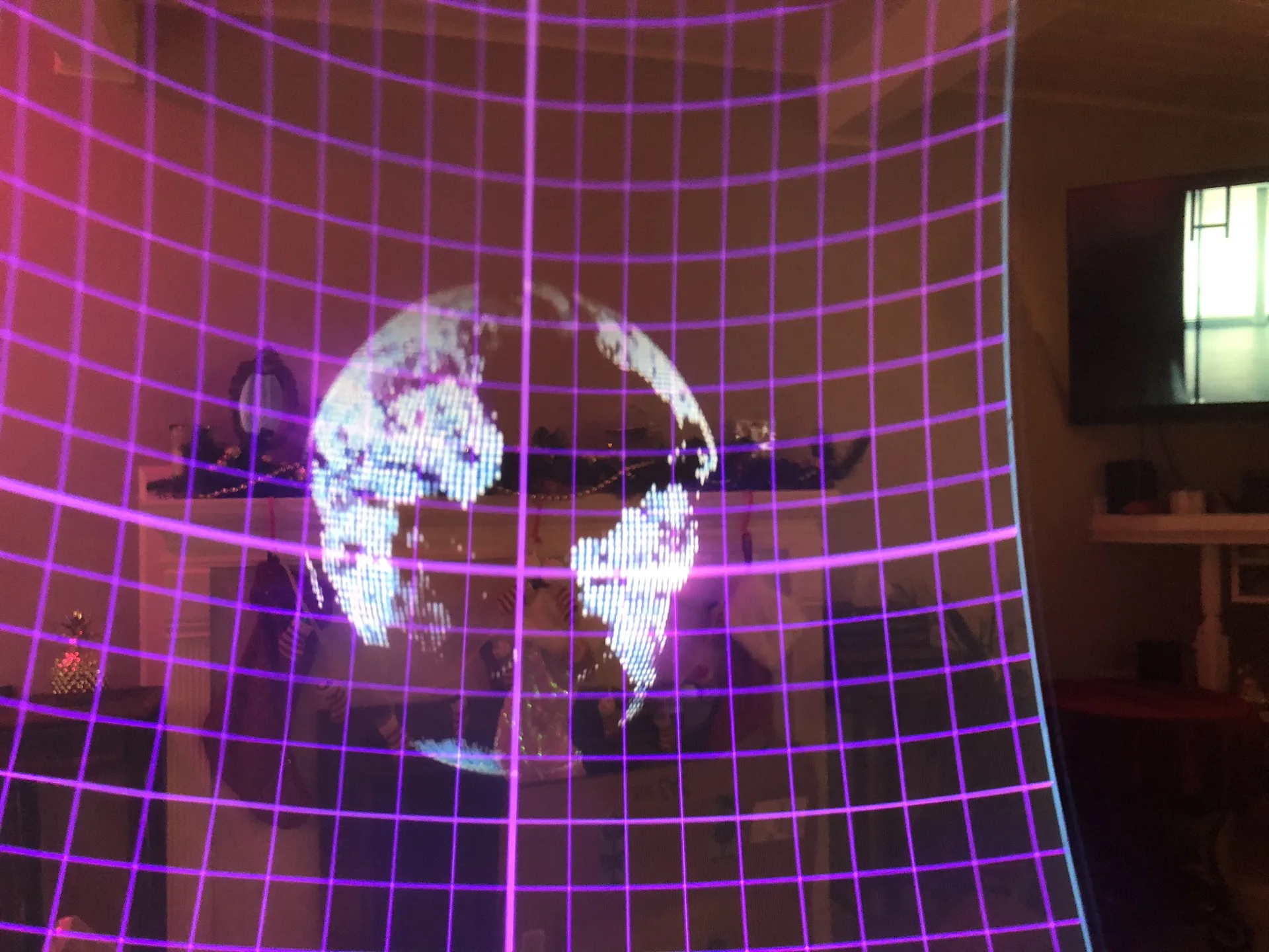 View through a HoloFlect visor: a glowing purple grid and a speckled globe float in front of a living room.