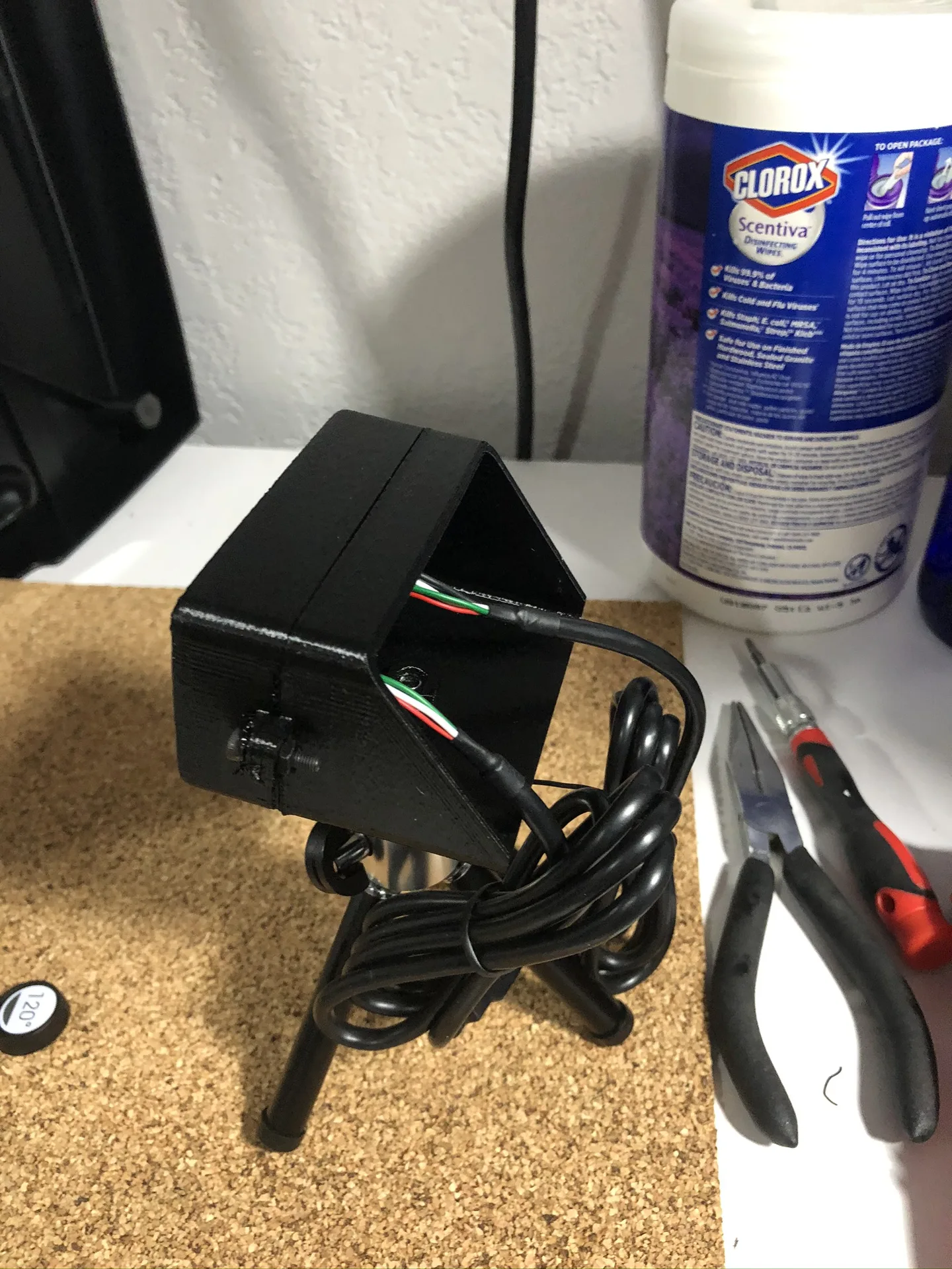 The back of the black enclosure on its tripod, with a cable leading out of an open rear panel.